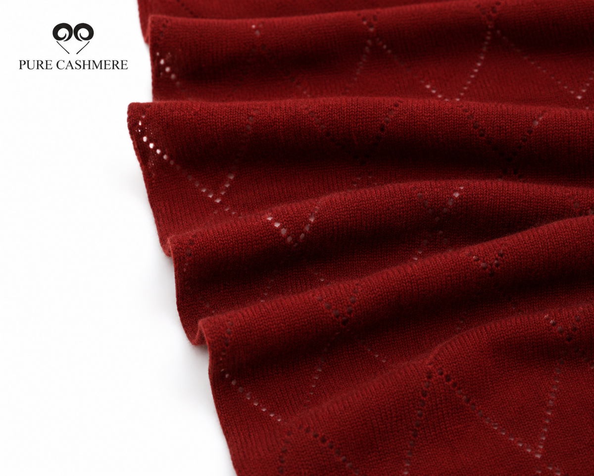 Close-up of burgundy cashmere knit fabric showing the weave and drape folds.